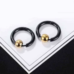 Sort ørering i stål med gylden kugle.